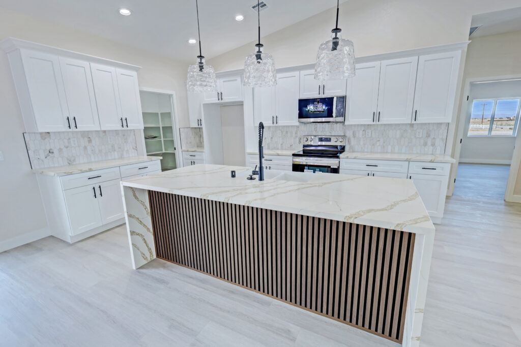Kitchen with a quartz island and white shaker cabinets in an ICH home